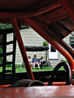 People sitting in porch swing, seen through racecar window