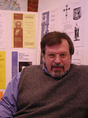 
Vice President of Student Services Gar Kellom sits before a collection of flyers from seven years of "Men's Lives" lectures. (MPR Photo/Jeff Horwich)