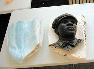 
The head and upper chest of one figure, completed in wax.  The wax is of a color similar to what the final bronze
will look like. The wax model will be encased in the final mold, and then burned away and replaced by molten bronze.
 (MPR photo/Bob Kelleher)