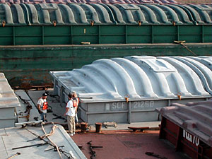 
Three workers attempt to secure all of the barges together.  Unless they're properly tied, the trip down river can be hazardous. (MPR Photo/Erin Galbally)