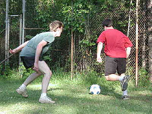 
Adam Ritscher, in red, tries to slip past Andy Olson. Usually five or six players show up for the weekly soccer game. When it's only two players, they get an extra workout. Ritscher and Olson play for two hours - until the score is about 30-30, using Commie Soccer counting. (MPR Photo/Chris Julin)