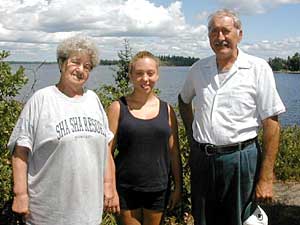 
Etta Jean and Norbert Goulet stand with their great-granddaughter, Stori, (center) on a hill overlooking Rainy Lake. The Goulets say when their 25-year lease runs out in September, they won't set foot back on the island they've called home for four decades. (MPR photo/Tom Robertson)