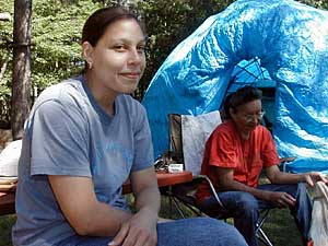 
Leslie Harper relaxes at her camp site at the Mille Lacs Culture and Language Camp near Rutledge, Minnesota. Harper, of Cass Lake, is learning the Ojibwe language through a new program that pairs her with a fluent-speaking elder. (MPR photo/Tom Robertson)