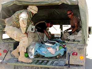 
Lt. Col. Andy Wolkstein (far left) and  Maj. Sam Sapio (right) check on unidentified military member as the patient awaits a flight to Germany. (Photo/Maj. Gene Delaune)
