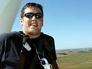 
Tyler Juhl sits on top of a wind turbine, 200 feet
above the ground.  Juhl climbs four or five machines a day, to make sure they're working properly. The wind turbines are
owned by Woodstock Wind Farm. (MPR Photo/Mark Steil)