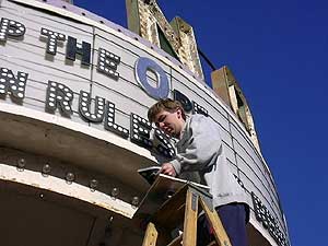 
City councilor and businessman Donny Ness puts up a new sign on the marquee of the NorShor Theatre.  The sign is advertising three stores opening on the same block as the theater. (MPR Photo/Stephanie Hemphill)