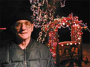 
Ralph Roubal has 7,500 lights on the trees and shrubs surrounding his house.  The 68-year-old says Christmas light services are fine for some people, but he enjoys the work of putting up his lights.  It's hard work, but he says it's fun.  (MPR Photo/Tim Post)