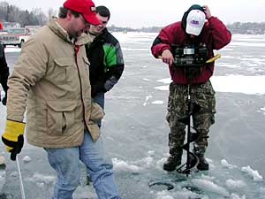 
These fishermen break out of the solitude of their ice houses to drill another hole in the ice.
 (MPR Photo/Annie Baxter)