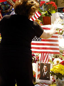
 A women takes time to reflect in front of a shrine honoring former U.S. President Ronald Reagan at the Gates Kingsley Moeller Murphey Mortuary where Reagan's body was being held.  (Photo by Sandy Huffaker/Getty Images)