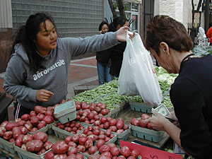 
Yu Vang helps a customer at one of downtown St. Paul's weekday farmes' markets.  Yu, her two sisters, and their parents help out with the farm owned by their brother in the southwest fringes of the metro area. (MPR Photo/Jeff Horwich)