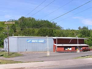 
Bob Berghammer's store stands just inside the high railroad grade that marks the south wall of the Canisteo pit.  Beyond the green rise in the rear, water has risen 15 feet above the town. (MPR Photo/Bob Kelleher)