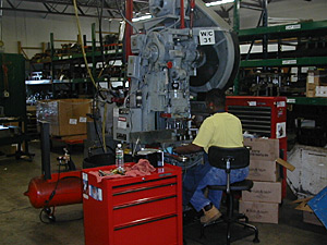 
A worker mans a machine at E.J. Ajax & Sons.  Even though he has added staff, Erick Ajax is also focused on increasing productivity.  During the downturn, he trained his employees to run multiple machines at one time. (MPR Photo/Jeff Horwich)