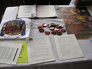 
A table covered with buttons, flyers and other give-aways helps draw the curious.  When they stop, volunteers will ask about their voter registration status, and help them get registered if they are not. (MPR Photo/Bob Kelleher)