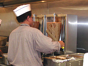 
Adel Hegazi shaves lamb into thin slices. (MPR Photo/Julie Siple)