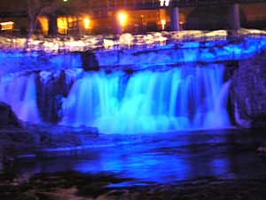 
Falls Park at night is a popular destination for couples of all ages.  The parks department decorates every tree for the holidays and spotlights change the color of the water. (MPR Photo/Cara Hetland)