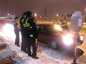 
Each driver stops for less than a minute at the checkpoint. Police officers quickly assess drivers. They depend on the smell of alcohol, or signs a driver is impaired, to determine if field sobriety tests should be done.   (MPR photo/Dan Gunderson)