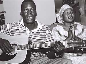 
Haditha Suliman often works two full time jobs so she can send money to her family in Sudan. Here, Suliman is in prayer as her son plays a guitar and sings. "The photograph really conveys a sense of her devotion, and how much prayer means to her and how much prayer gives her strength," says Lindholm. (Photo courtesy Meg Luther Lindholm)