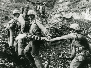 
Starting to climb Mt. Suribachi.  Photographer Lou Lowery, fearing that the patrol might not reach the summit, asks the men to hold up the flag for a picture. Charles Lindberg is first in line. (Photo: Lou Lowery, from the collection of Charles Lindberg)