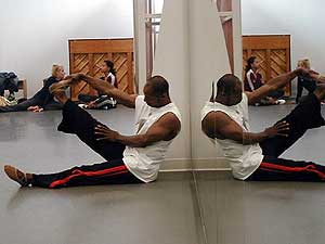 
Uri Sands stretches before a duet with his wife Toni (seen in the background), while others dancers rehearse. (MPR Photo/Marianne Combs)