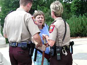 
Gina Kiser, a 25-year veteran of the Human Services Department, stood on the Capitol steps with her dog and a sign that read, "Will work for food." She was challenged by two state troopers who told her she had to take her dog off the Capitol grounds. The confrontation escalated, and Kiser was led away in handcuffs. (MPR Photo/Art Hughes)