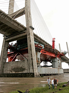 
 Towboat and shipyard workers John (L) and Michelle Welborn (C) walk with Robert Rishel (R) away from the Mobile Bay after an oil rig tore free of its moorings as Hurricane Katrina lashed the Alabama coast before surging downriver and smashing into a suspension bridge. ( PAUL J. RICHARDS/AFP/Getty Images)