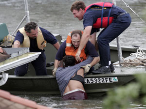 
 Rescue workers pull a woman from the water who was hanging onto the roof to escape the rising flood waters from Hurricane Katrina.
 (Photo by Chris Graythen/Getty Images)