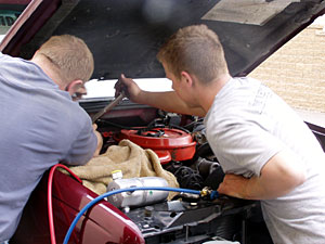 
Two students work under the engine of a truck at the Newgate School.   (MPR Photo/Toni Randolph)