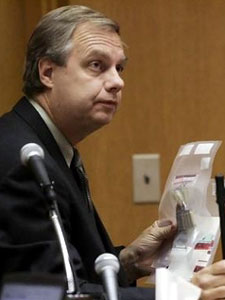 
Wisconsin state crime lab weapons expert William Newhouse holds a gun and some shells as he testifies during the Chai Soua Vang murder trial. (Pool photo/Stormi Greener)