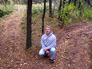 
Warroad resident Jeff Siverhus sits at the junction of two trails on a hillside in the Belrami Island State Forest. Siverhus says the trail to the right is the main trail. The one to the left was made illegally and is now commonly used. (MPR photo/Tom Robertson)